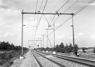 803836 Gezicht op de spoorlijn bij Deurne, met een speciale constructie van de bovenleiding, waarbij de draagkabel ...